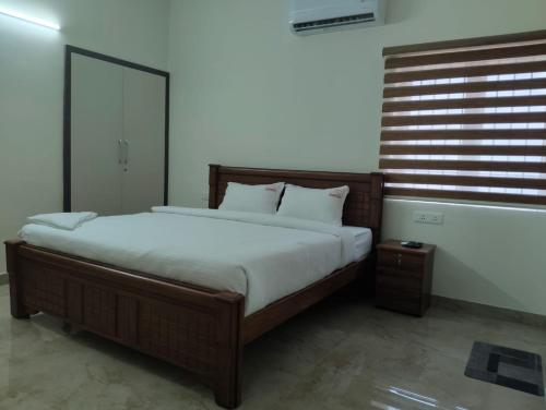 een slaapkamer met een groot bed met witte lakens bij Amaira Studio living - Coimbatore in Coimbatore