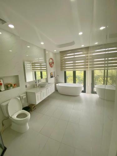a bathroom with two sinks and a tub and a toilet at UY LONG Homestay Grand World Phú Quốc in Phú Quốc