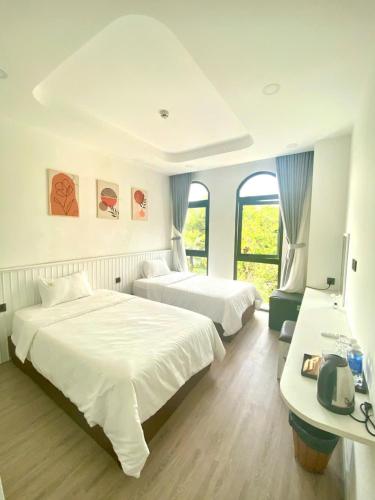 a hotel room with two beds and a desk at UY LONG Homestay Grand World Phú Quốc in Phú Quốc