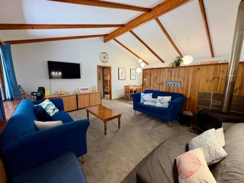 a living room with blue couches and a tv at Macbeth Family Stay in Geographe