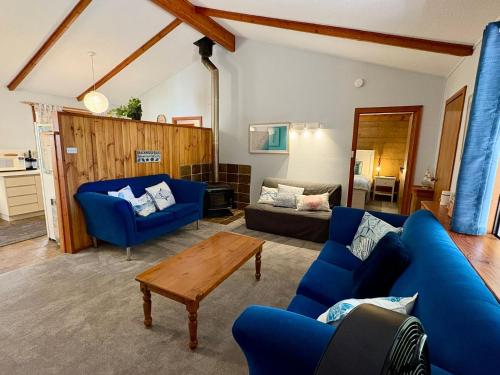 a living room with blue couches and a table at Macbeth Family Stay in Geographe