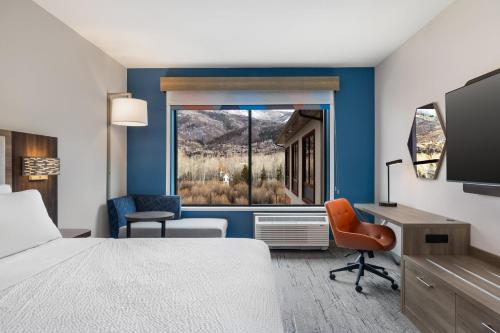 a hotel room with a bed and a desk and a window at Holiday Inn Express & Suites Steamboat Springs by IHG in Steamboat Springs