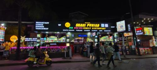 a group of people walking down a street at night at Marlin Beachway Rooms- Baga Beach in Baga