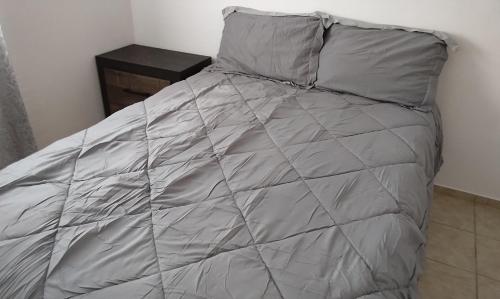 a bed with a gray comforter and pillows at Claudette Guest House in Michelson