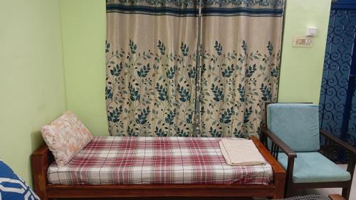 a room with a bed and a chair and a curtain at Cherry Blossom in Puducherry