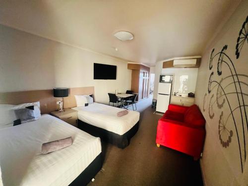a hotel room with two beds and a table at Pavilion Hotel Wagga Wagga in Wagga Wagga