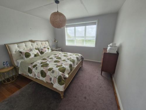 een slaapkamer met een bed en een raam bij Country Harbourside Escape in Whakapirau