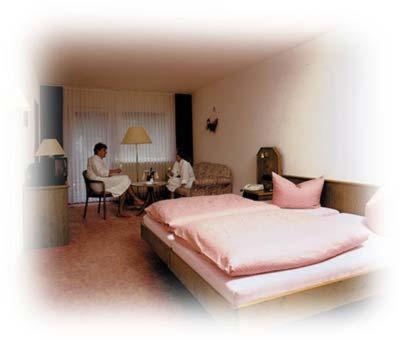 a bedroom with a bed and a person sitting at a table at Hotel Burg Waldau in Grasellenbach