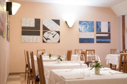 a dining room with white tables and chairs and paintings at Hotel Ristorante SASSO in Bovolone