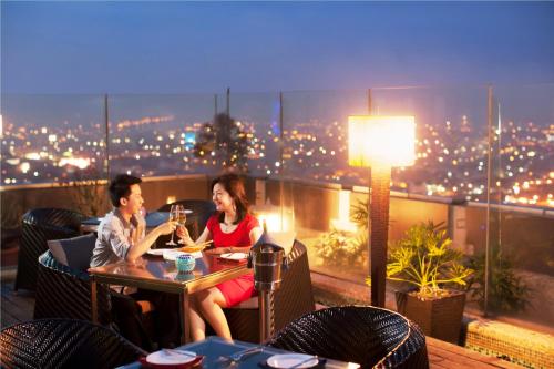 two women sitting at a table on a balcony at night at Cambridge Hotel Medan in Medan