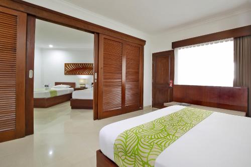 a bedroom with two beds and a large window at Dewi Sri Hotel in Legian