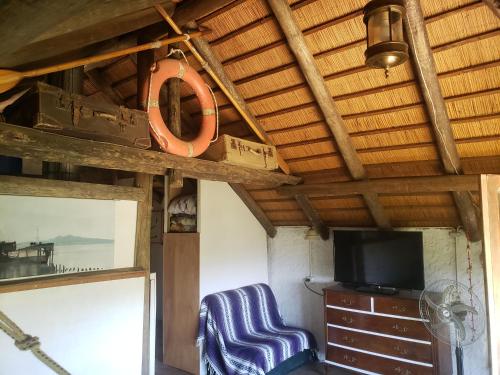 Una habitación con una silla y un televisor y un techo de madera. en QinLing en playa hermosa y playa verde, en Playa Hermosa