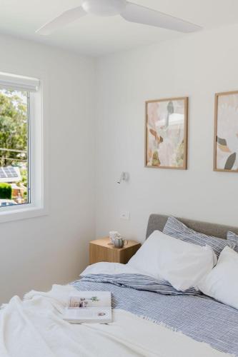 a white bedroom with a bed and a window at Ocean Haze - Putting Green, Firepit, Beach location in Mollymook