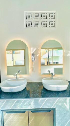 two sinks in a bathroom with two mirrors at Cosy Hostel in Ko Tao