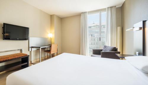 a hotel room with a bed and a desk and a television at Ilunion Auditori in Barcelona