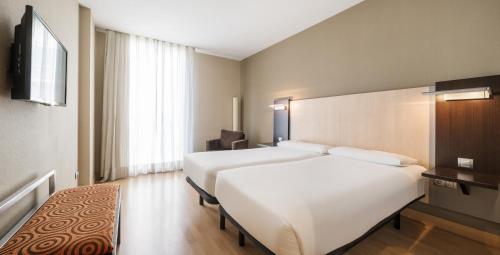 a hotel room with two beds and a television at Ilunion Auditori in Barcelona