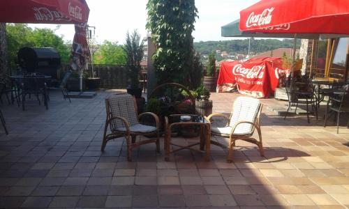 a patio with a table and chairs and cocacola umbrellas at Motel Podkova in Klobouky u Brna