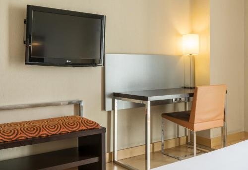 a room with a desk and a television on a wall at Ilunion Auditori in Barcelona