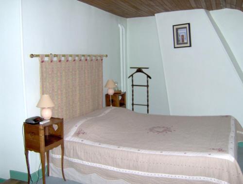 a bedroom with a bed and a nightstand with two lamps at Au clos des colombages in Athis