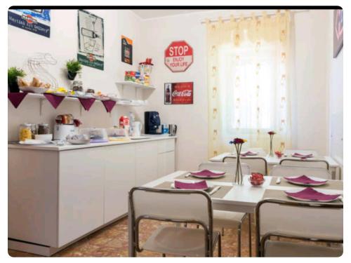 a dining room with a table and chairs and a kitchen at Bed & Breakfast Fontanarossa Airport -Private Parking- in Catania