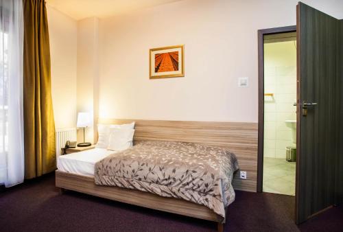a bedroom with a bed and a door to a bathroom at Hotel Arsenał in Gliwice