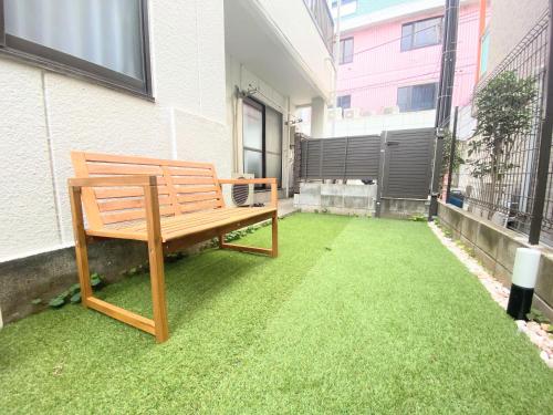 a wooden bench sitting on the grass in a courtyard at F-City 中葛西 I in Tokyo