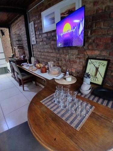 een tafel met glazen en een tv tegen een bakstenen muur bij Hostel Lapa 166 in Rio de Janeiro