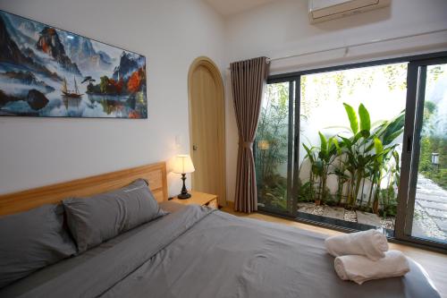 ein Schlafzimmer mit einem Bett und einem großen Fenster in der Unterkunft Trăng Non Homestay in Phan Thiet