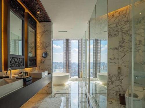 ein Badezimmer mit zwei Waschbecken, einer Badewanne und einer Dusche in der Unterkunft Balan International Hotel in Dujiangyan