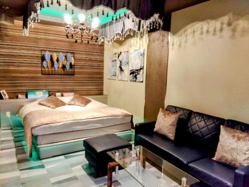 a bedroom with a bed and a couch and a chandelier at ホテルメイプル in Odate