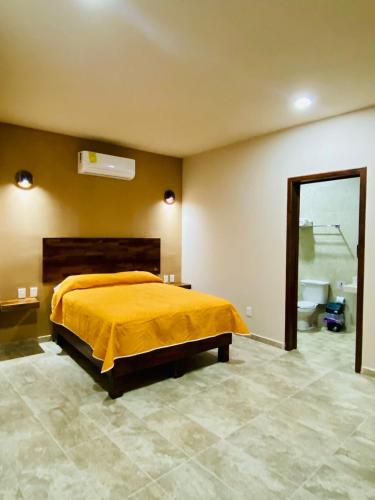 a bedroom with a yellow bed and a bathroom at Hotel Santa Cruz Mazunte in Mazunte
