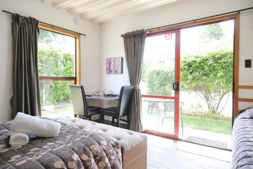 a bedroom with a bed and a table and a window at Forest Trail Lodge in Hanmer Springs