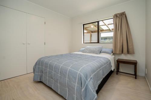 a white bedroom with a bed and a window at The Sunny Spot Kerikeri Central in Kerikeri