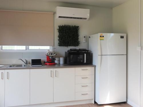 een keuken met witte kasten en een witte koelkast bij Little Birdy in Tawonga