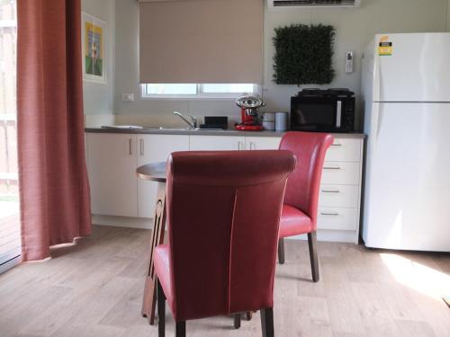 een keuken met een tafel en 2 stoelen en een koelkast bij Little Birdy in Tawonga