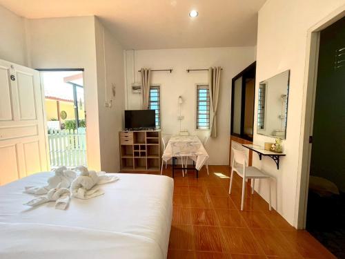 a bedroom with a white bed and a dining room at Yada House Alina Cottage in Nai Yang Beach