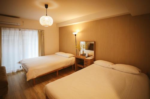 ein Hotelzimmer mit zwei Betten und einem Spiegel in der Unterkunft DL Shinsaibashi in Osaka