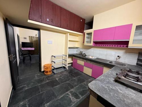 una cucina con mobili viola e rosa e un tavolo di Bluebell Homes A - 3 BHK Near to Calicut a Beypore