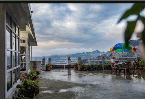a patio with a table and a colorful umbrella at Aashray kunj homestay in Jāmb