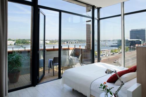 a bedroom with a bed and a balcony with windows at Eric Vökel Boutique Apartments - Amsterdam Suites in Amsterdam