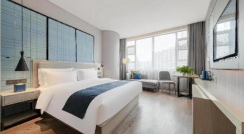 a bedroom with a large white bed and large windows at Echarm Hotel Wuhan Gaotie Jianshe 2nd Road Metro Exit in Wuhan