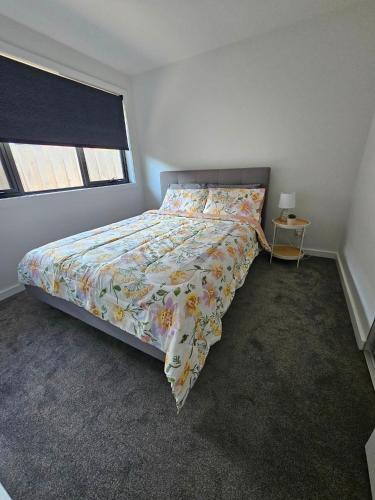 a bedroom with a bed with a floral comforter and a window at George Town Villa - Outdoor Alfresco - aircon FREE WIFI - Central location near MTB Trails in George Town