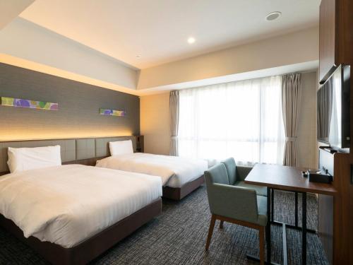 ein Hotelzimmer mit zwei Betten und einem Fernseher in der Unterkunft Comfort Hotel ERA Kyoto Toji in Kyoto