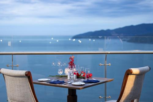 einen Tisch mit 2 Stühlen und einen Tisch mit Weingläsern in der Unterkunft Annova Nha Trang Hotel in Nha Trang