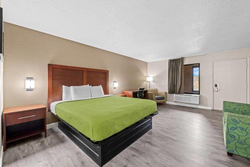 a hotel room with a bed with a green bedspread at Econo Lodge Kannapolis - Concord in Kannapolis