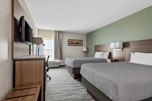 ein Hotelzimmer mit zwei Betten und einem Flachbildfernseher in der Unterkunft Quality Inn - Norman near University in Norman