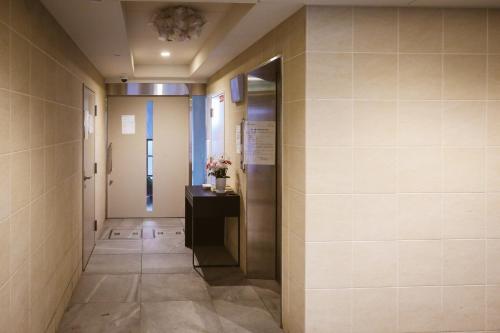 einen Flur in einem Gebäude mit einer Tür und einem Tisch in der Unterkunft DL Shinsaibashi in Osaka