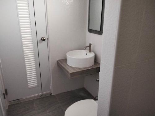une salle de bains avec un lavabo blanc et des toilettes dans l'établissement กัสเกรซ โฮมสเตย์, à Pak Chong