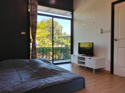 - une chambre avec un lit, une télévision et un balcon dans l'établissement กัสเกรซ โฮมสเตย์, à Pak Chong