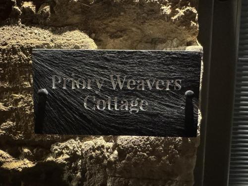 een bord met de tekst "Ragnar Weavers Collective" op een stenen muur bij Priory Weavers Cottage in Burford
